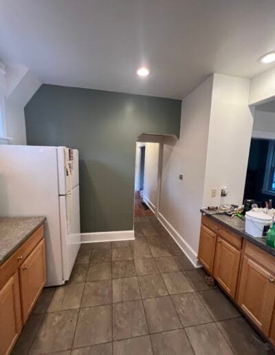 Kitchen with sage green accent wall and wooden cabinet